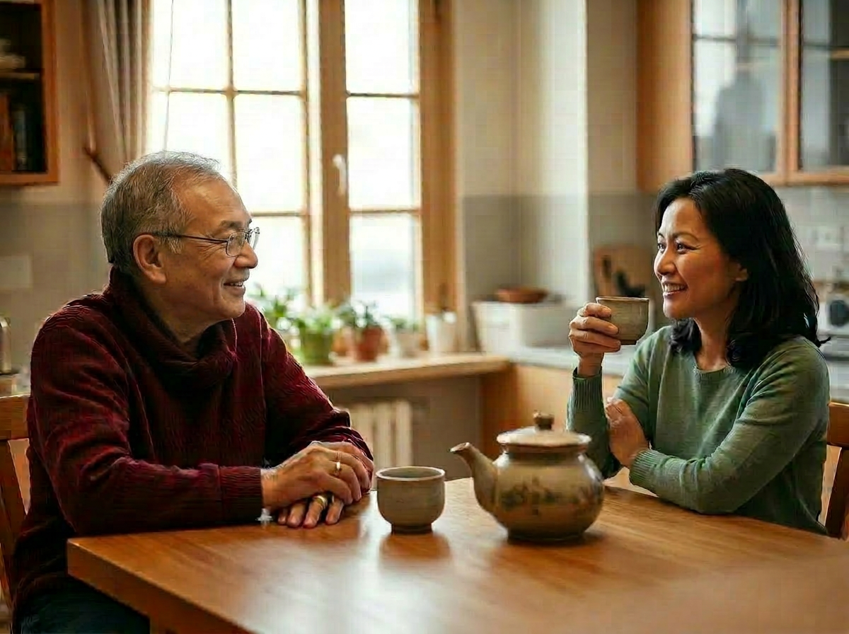 An elder Asian man sharing tea with his daughter while practicing speech therapy exercises at home